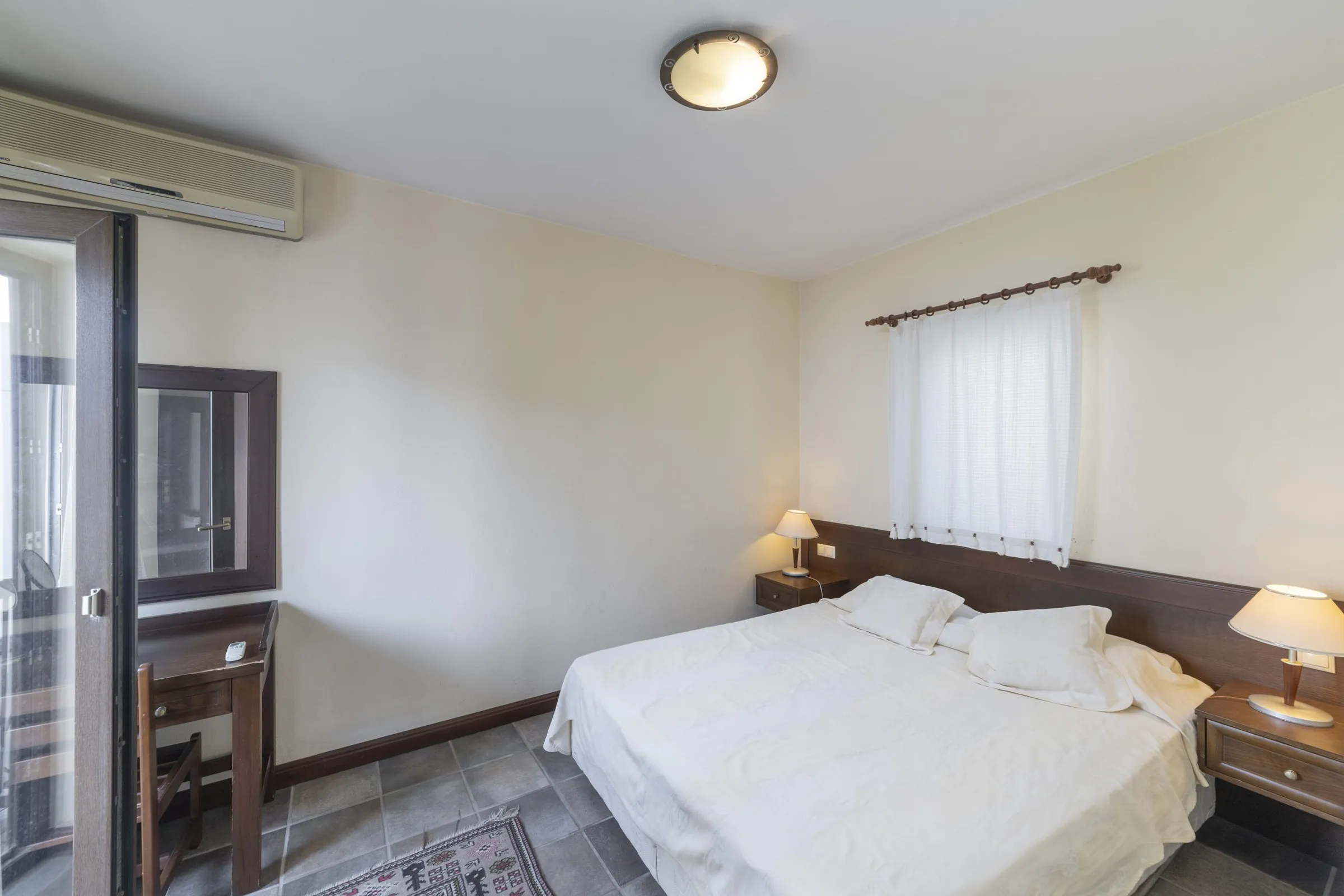Standart odanın çift kişilik yatağı ve balkon kapısı